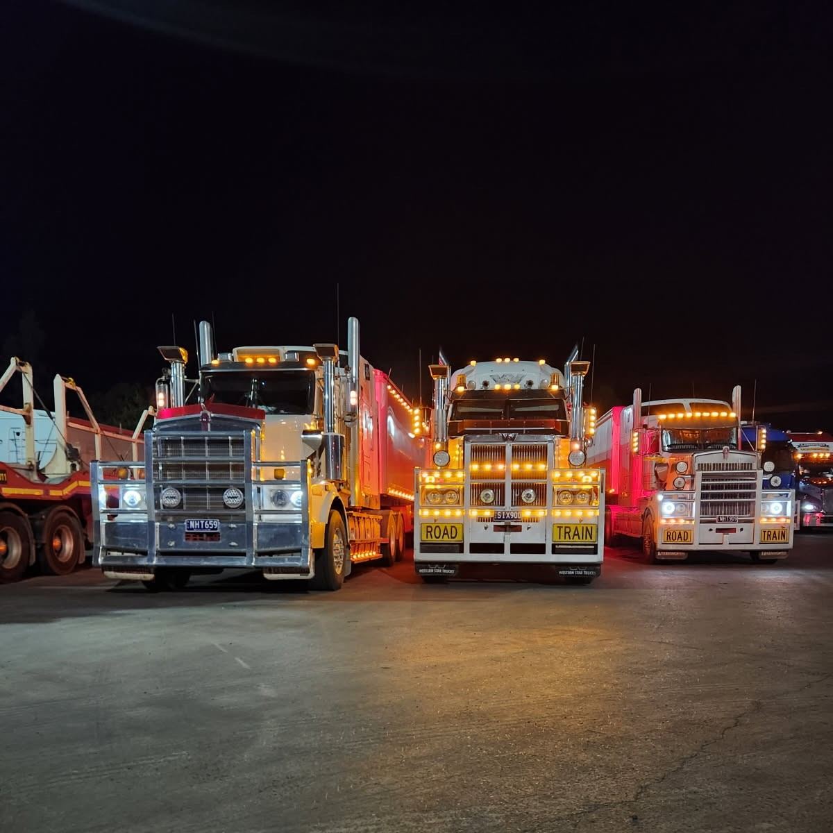 Nevens trucks lined up at night with lights on
